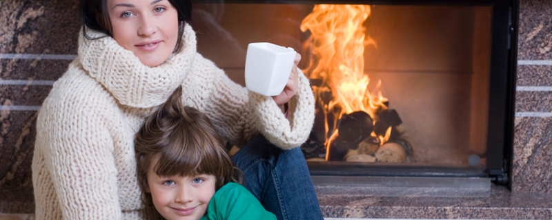 Woman and girl sitting in front of open fireplace